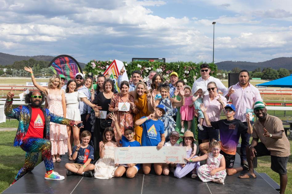 a group of people standing on a stage outside holding a large cheque