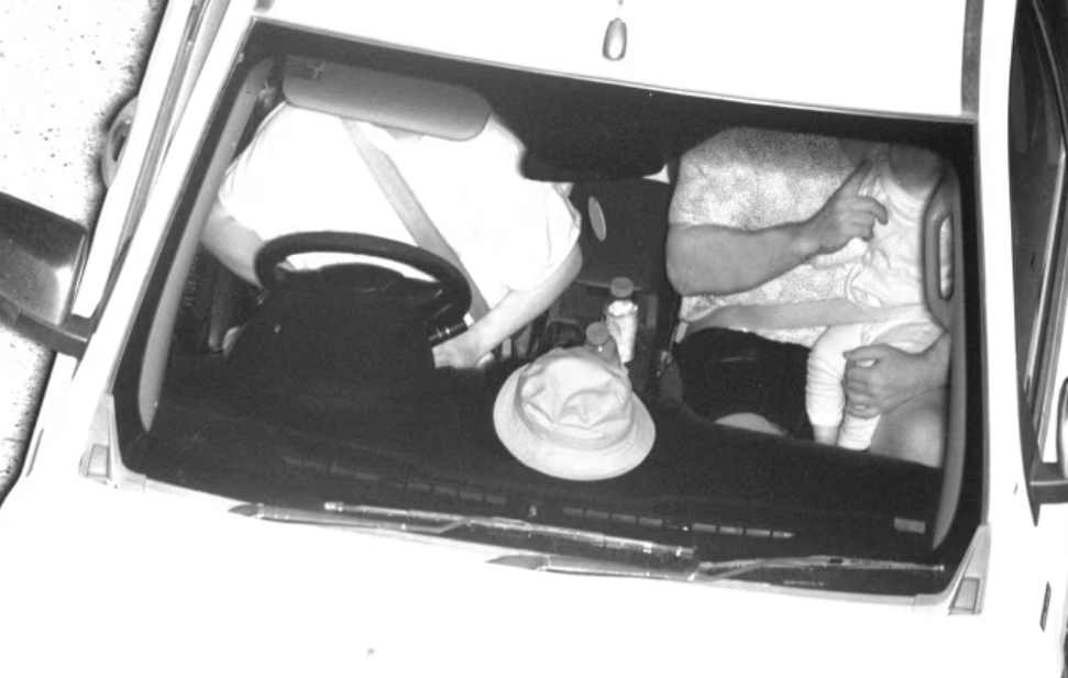 black and white image of person not wearing seatbelt correctly