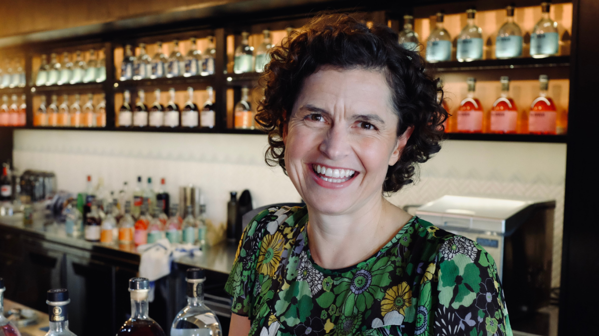 Woman in front of bar smiling.