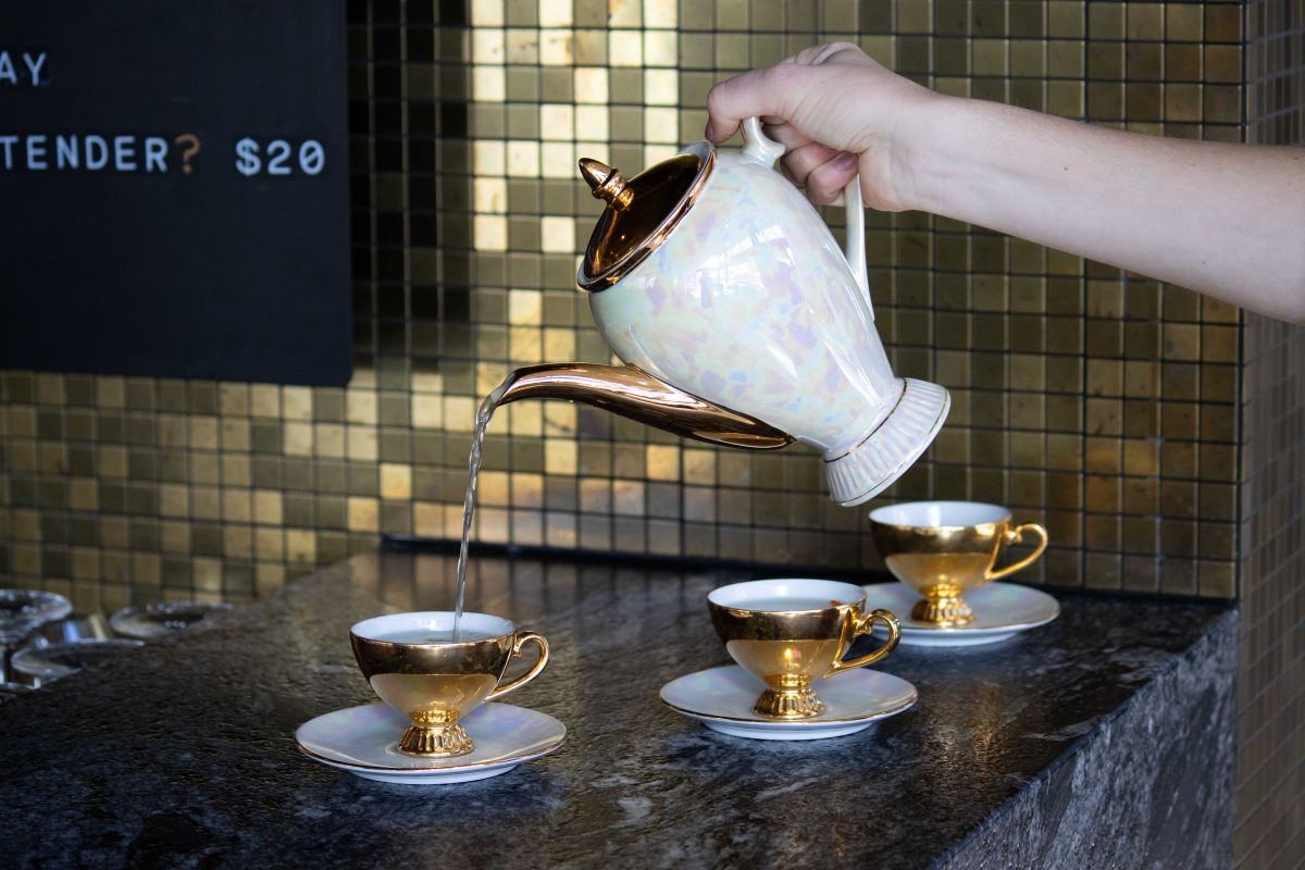 a hand pouring a teapot into a tea cup