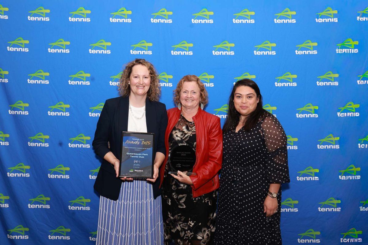 three people holding awards in front of a Tennis Australia media wall