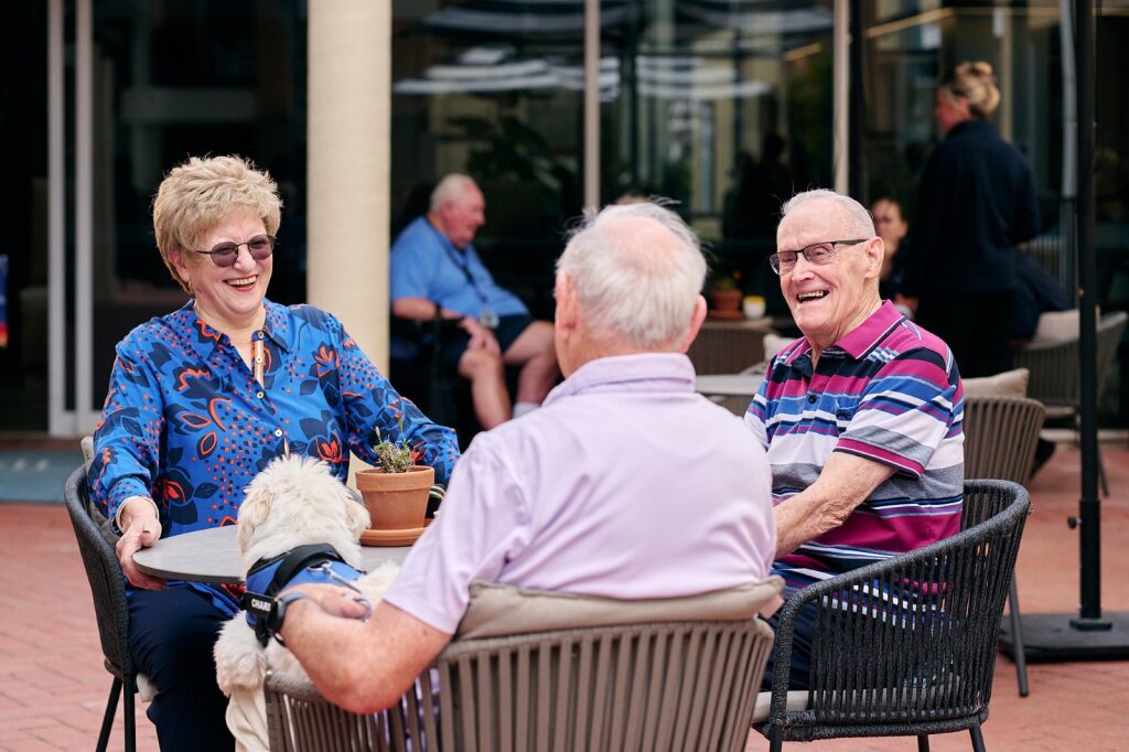 three people sitting at a coffee table outside