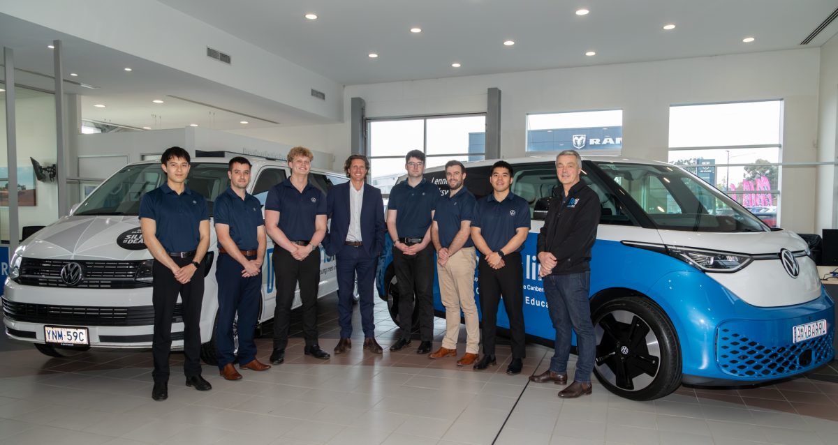 group of people standing in front of two vans