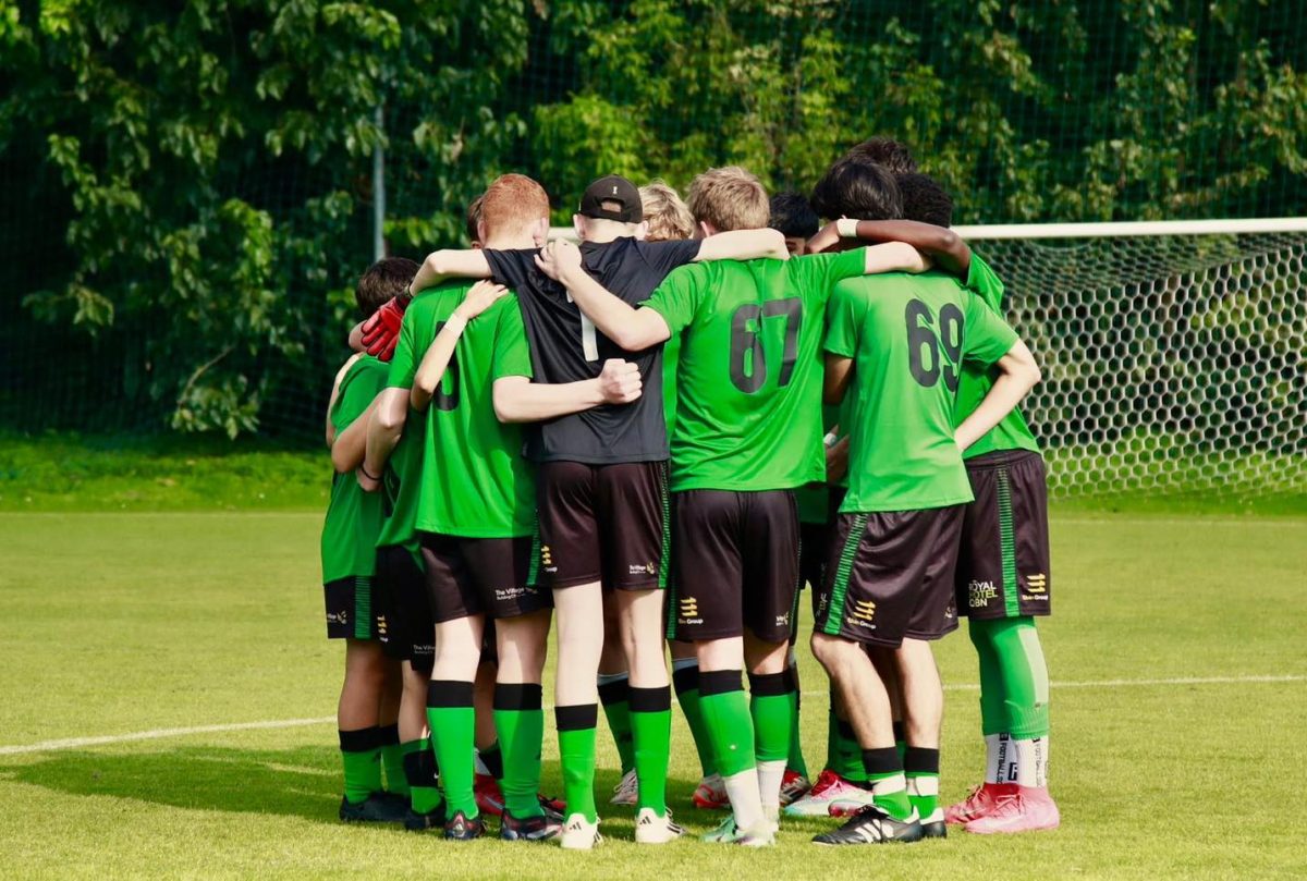 A group of young boys in soccer uniforms, standing in a circle