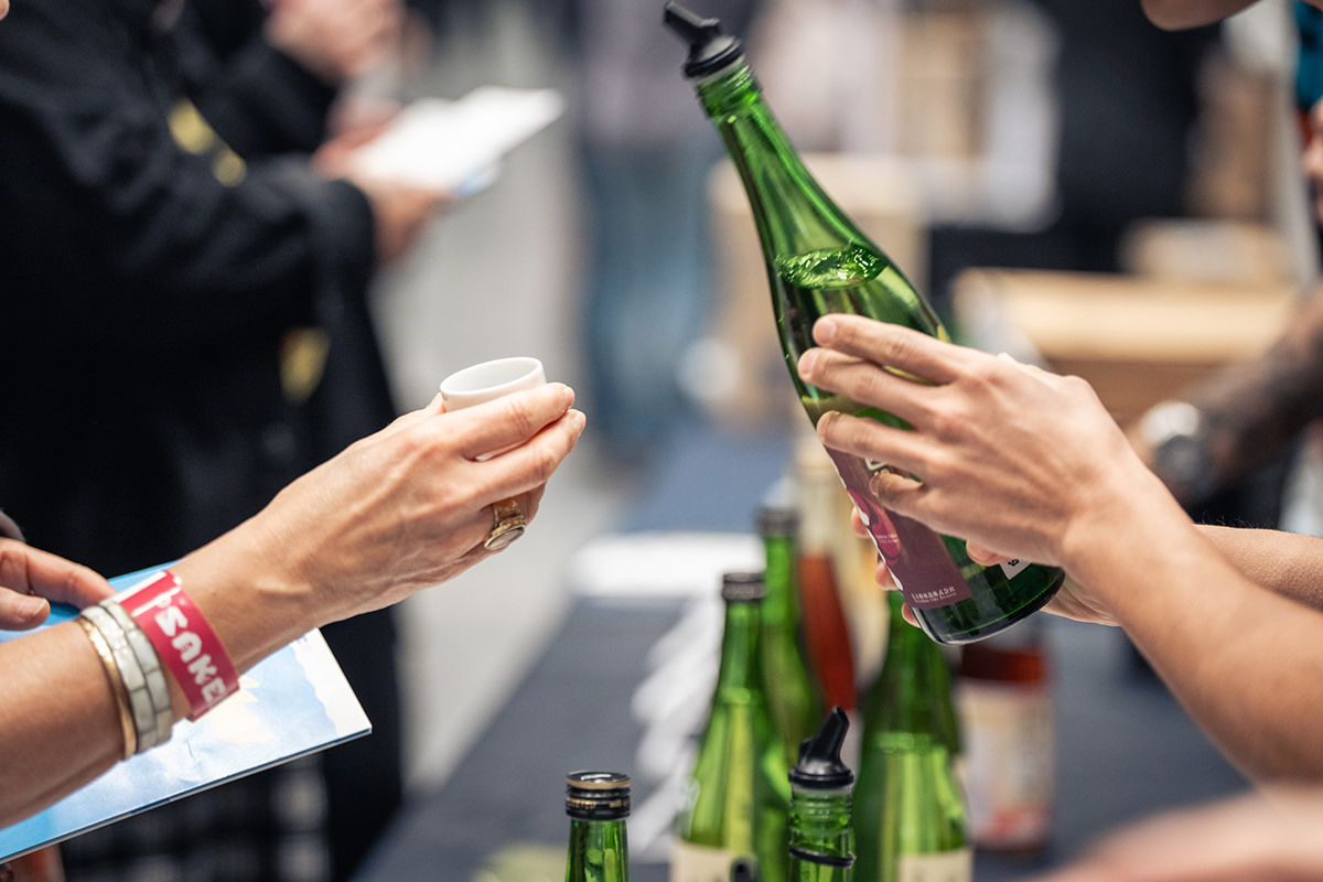 Hands holing a green sake bottle.