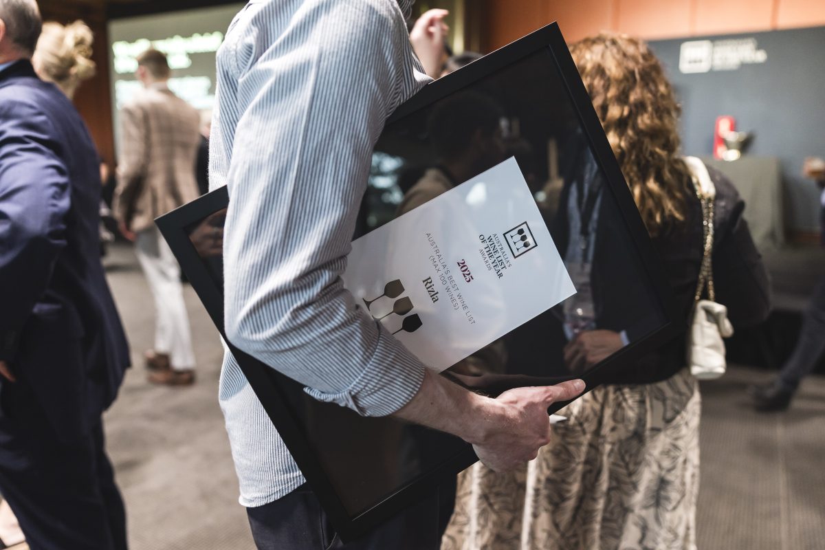 A large award tucked under the arm of a person wearing a white shirt. The award is for Rizla, and features the logo of the awards. 