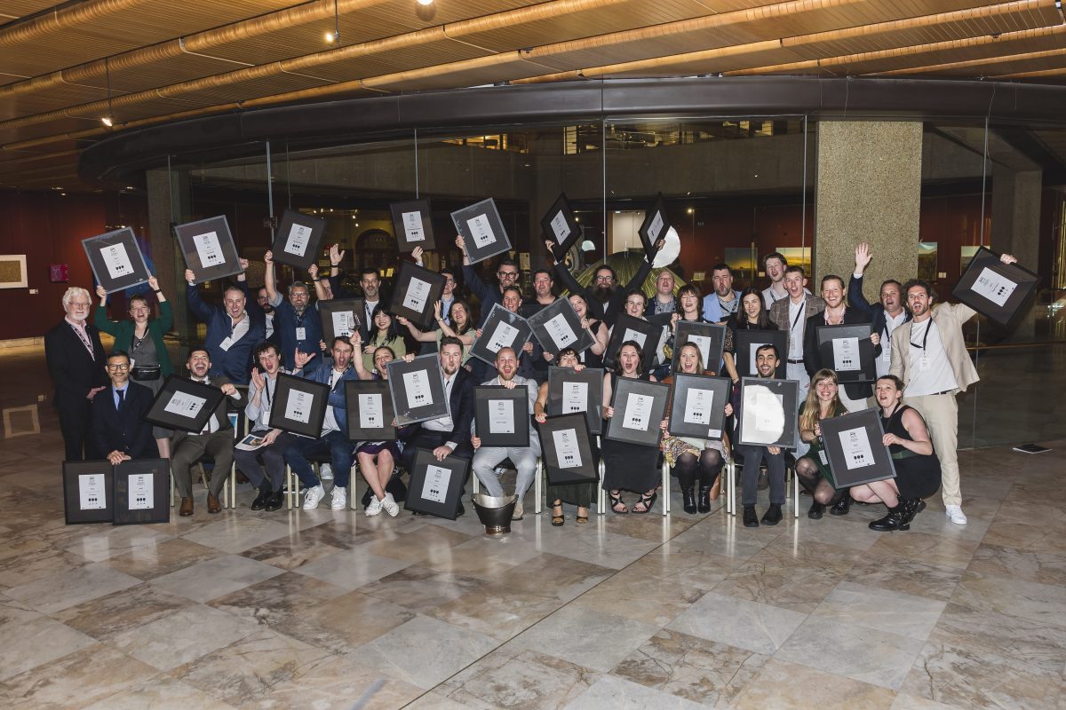 A group photo of people holding up black and white framed certificates. 