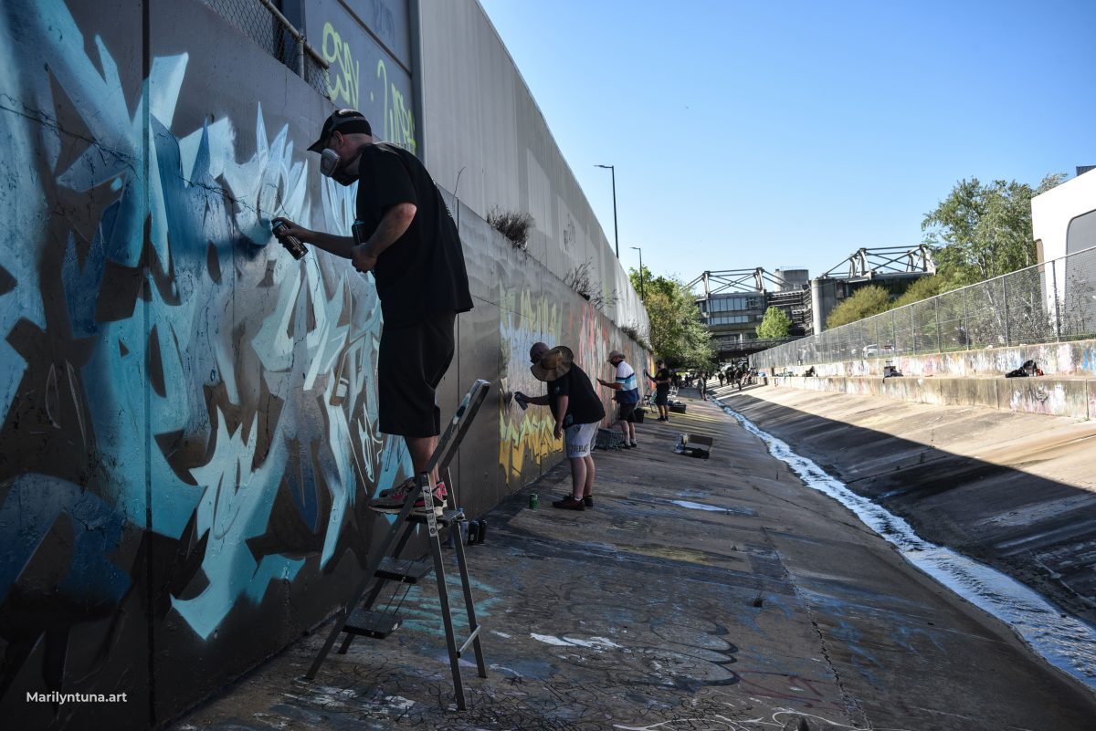 Artists wearing masks painting graffiti on a concrete wall