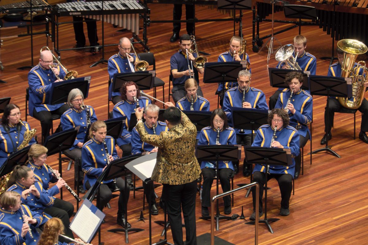 A conductor and a band on stage during a performance