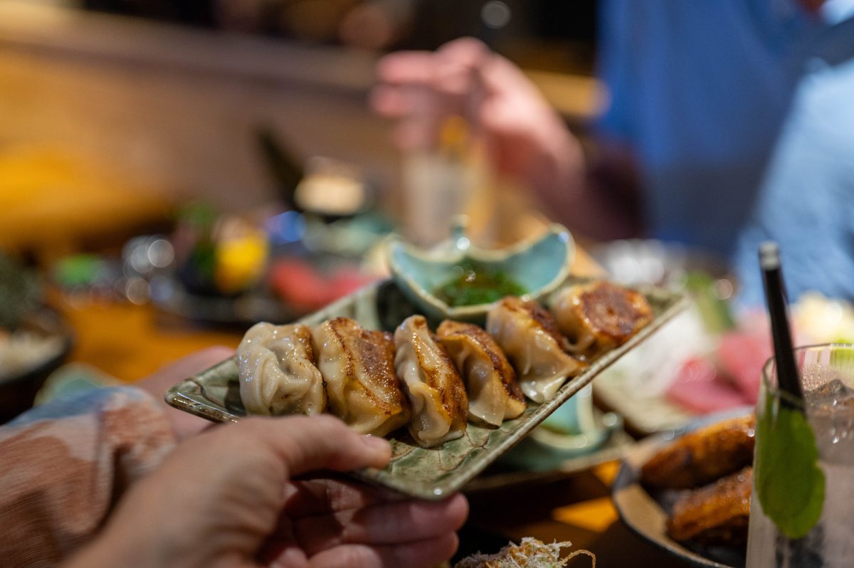 A plate of dumplings being handed across a table laden with food.