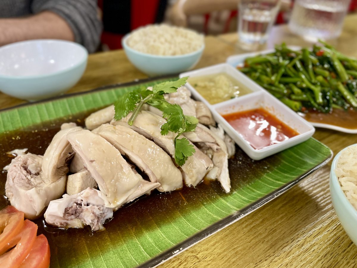 Sliced chicken on a green plate with sauces.
