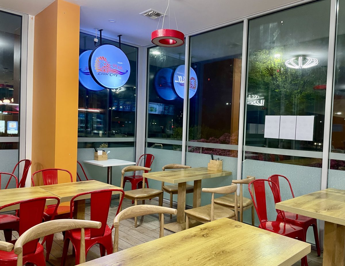 Interior of casual restaurant with red chairs, and light-up Lion City sign.
