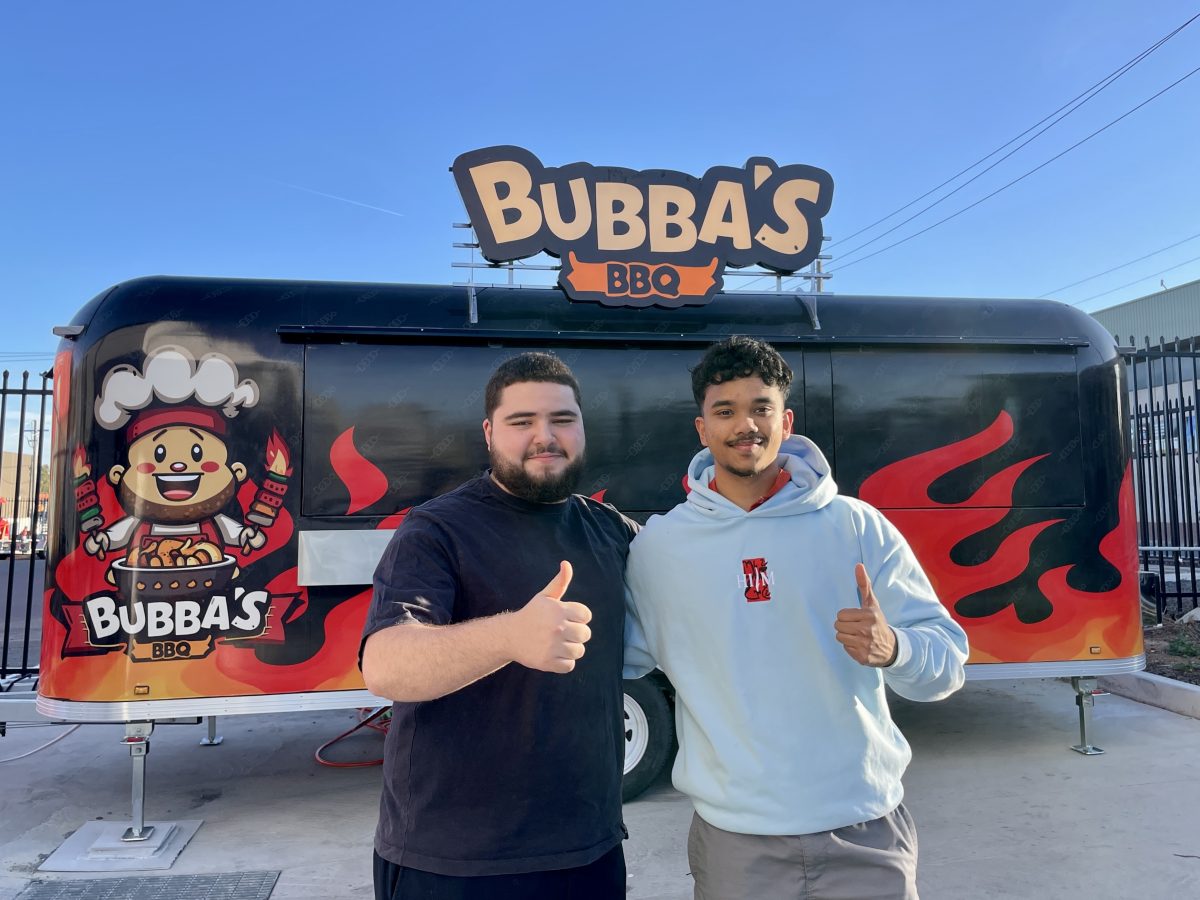Two young men stand in front of a black and red food truck with Bubba's BBQ Branding. They have one arm around each other and are giving a thumbs up.