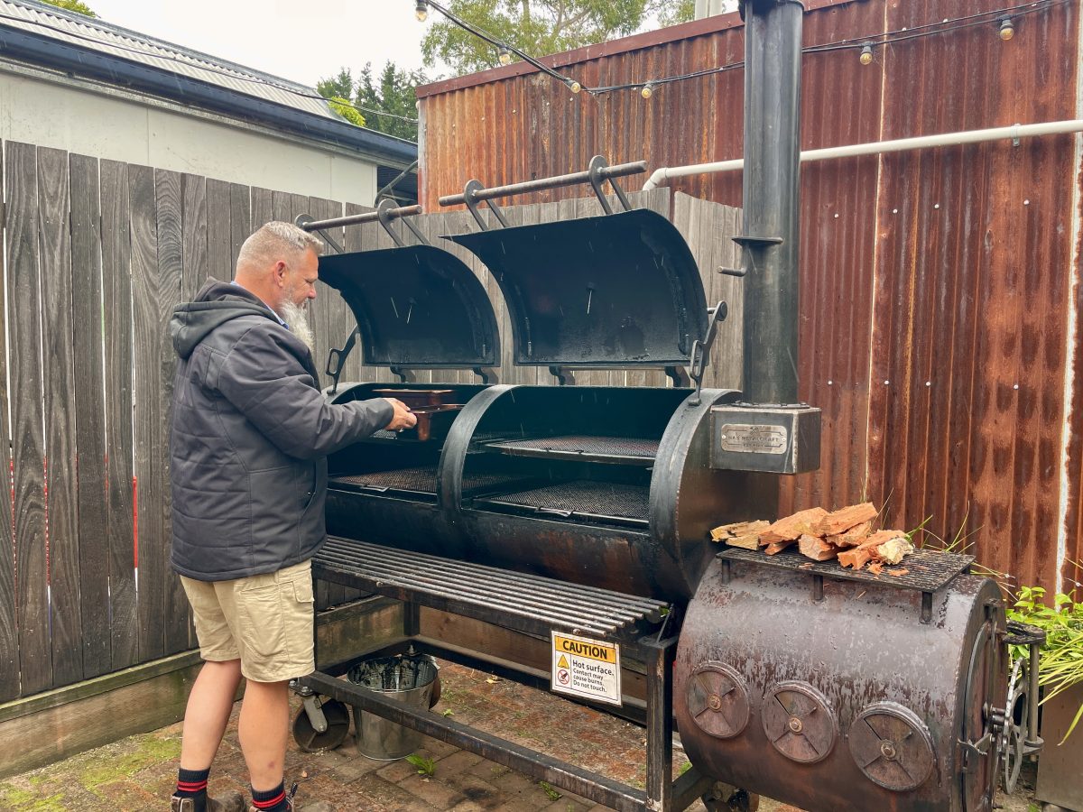 Man in raincoat stands at a smoker