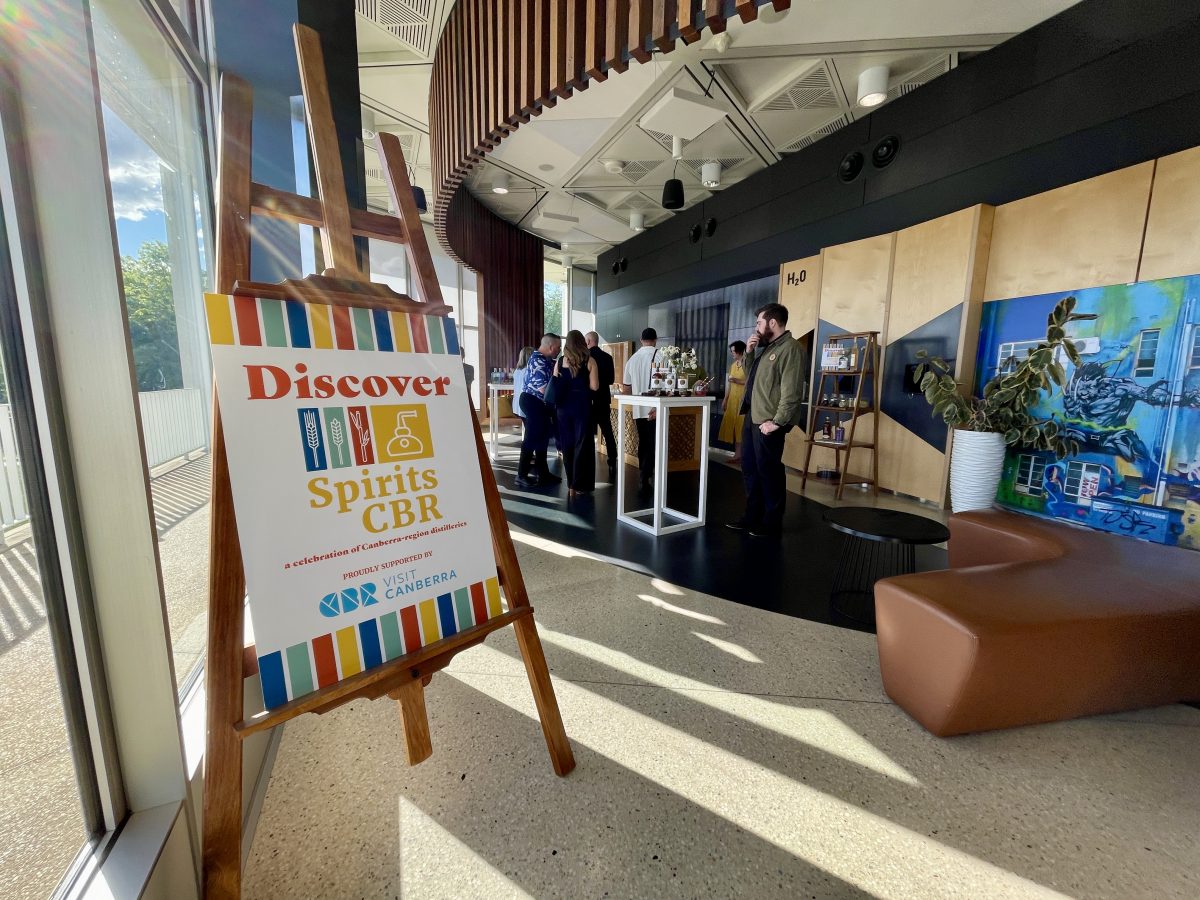 An sign reading 'Discover Spirits CBR, a celebration of Canberra Region distilleries. Supported by Visit Canberra'. The sign is colourful.