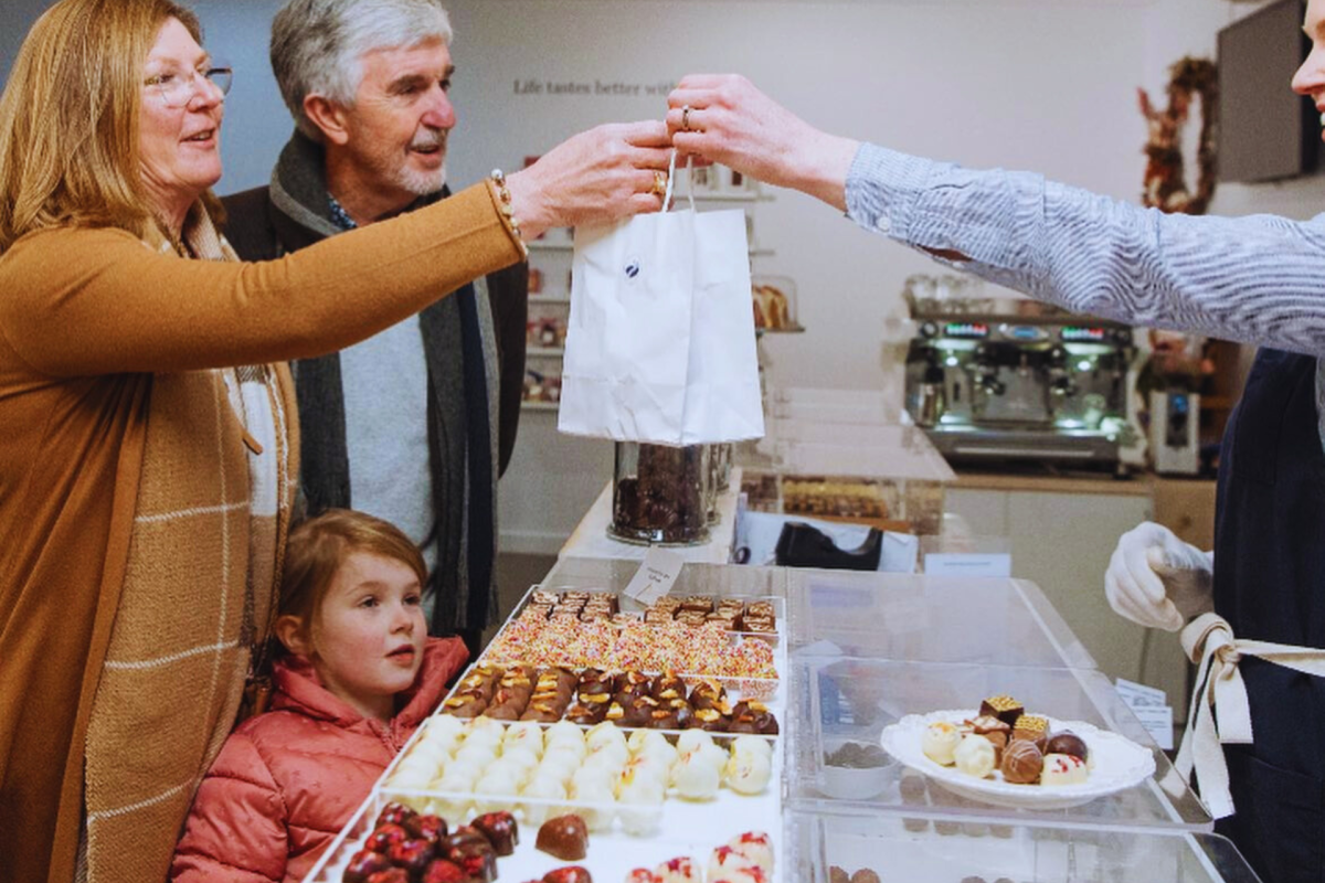 Man, woman and child buying chocolates.