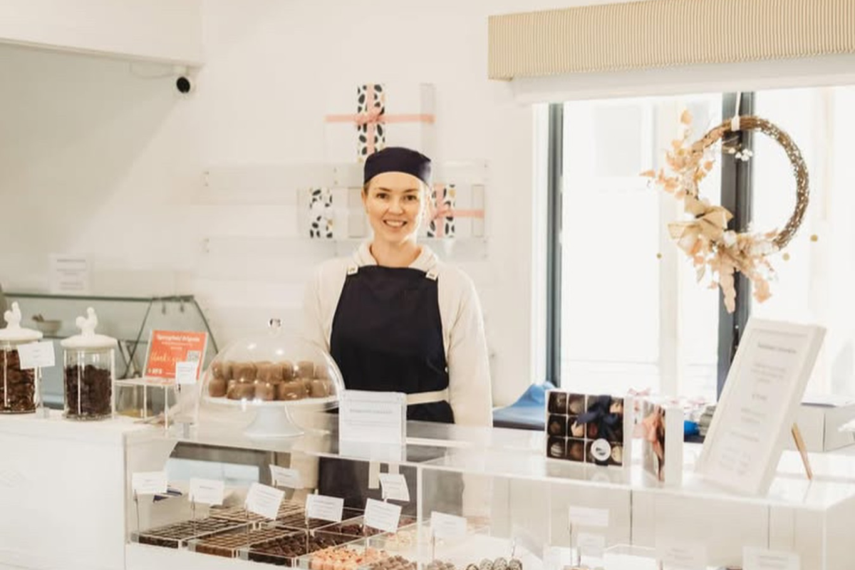 Woman stands in chocolate shop.