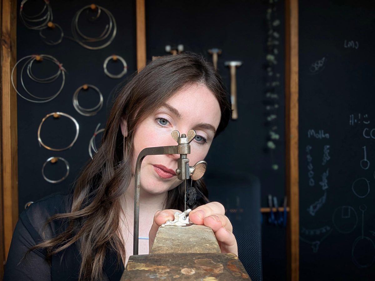 A woman with long dark hair working on a jewellery piece