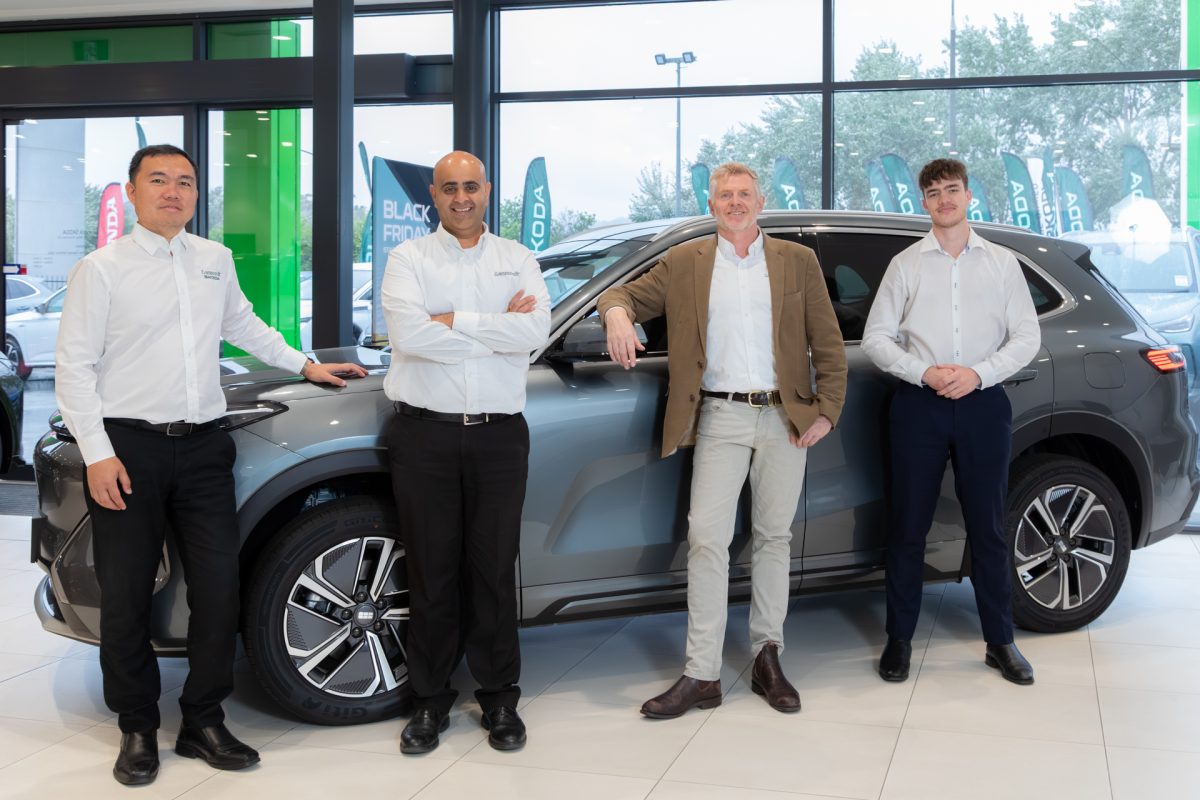 Group photo of 4 car salesman next a new car
