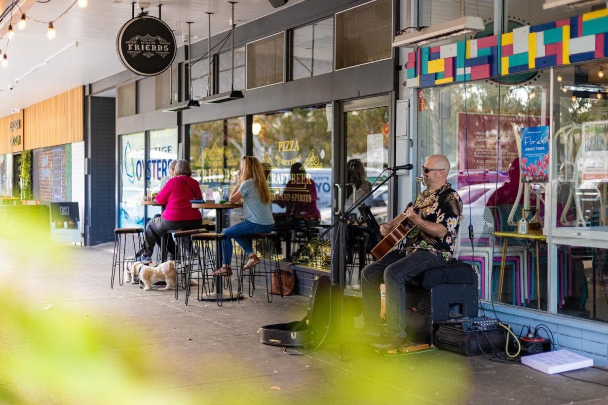 A man with guitar singing outside. 