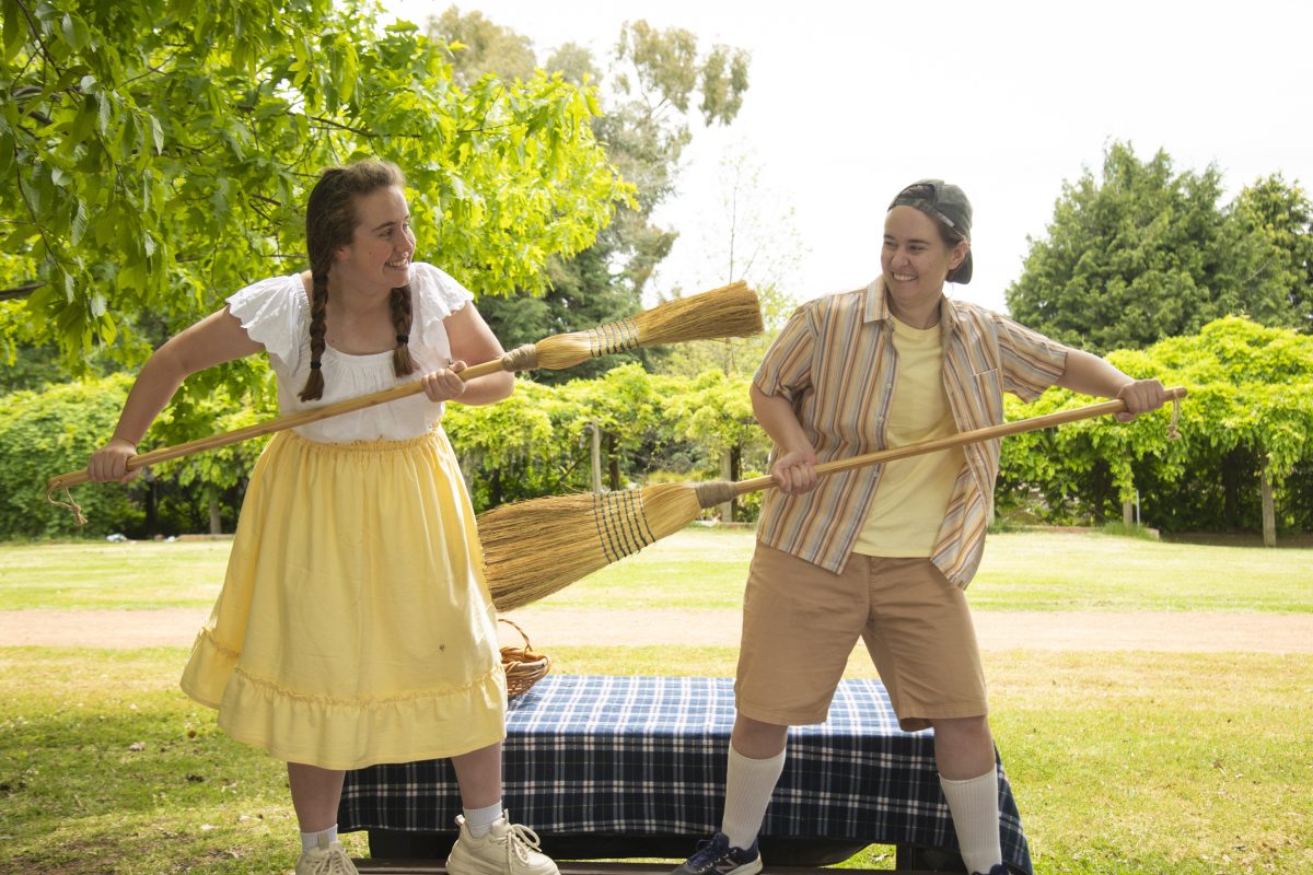 Hansel and Gretel actors roughhousing with brooms