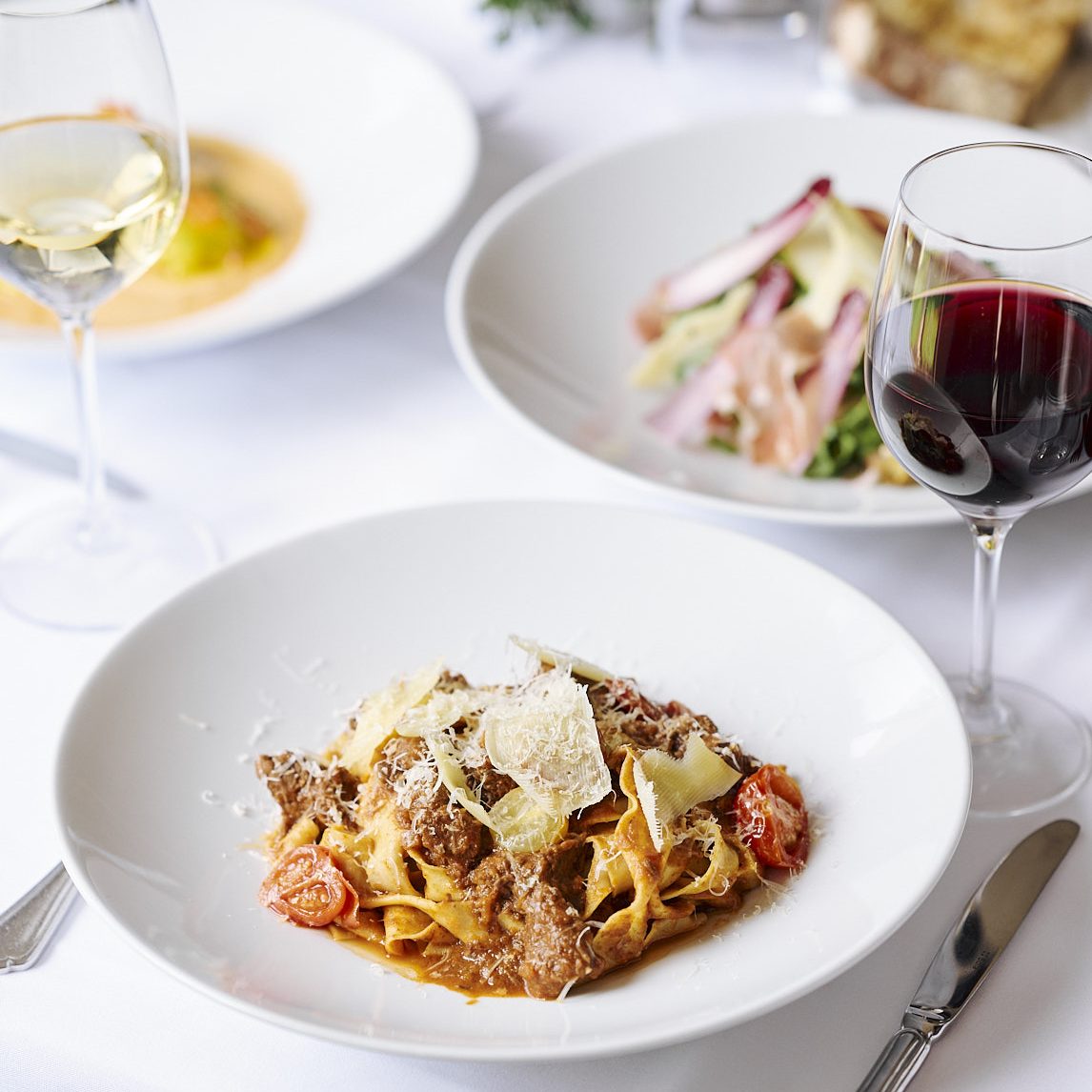 A bowl of pasta on white tablecloth.