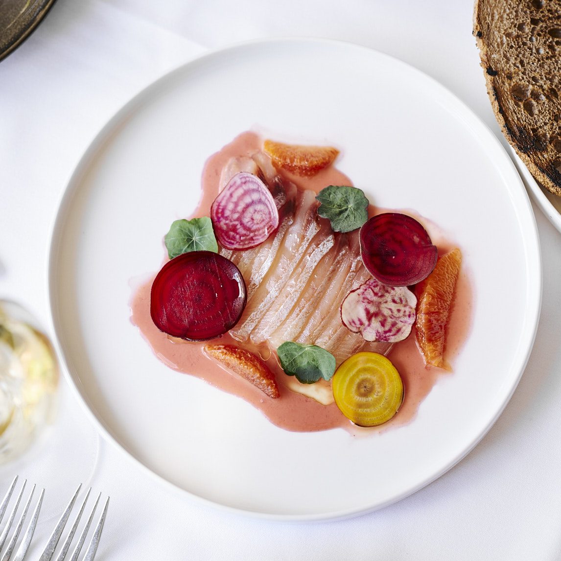 A plate of fish with thin rounds of colourful beetroot.