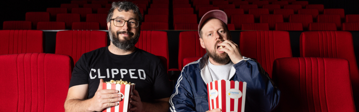 Two people sitting in cinema seats eating popcorn