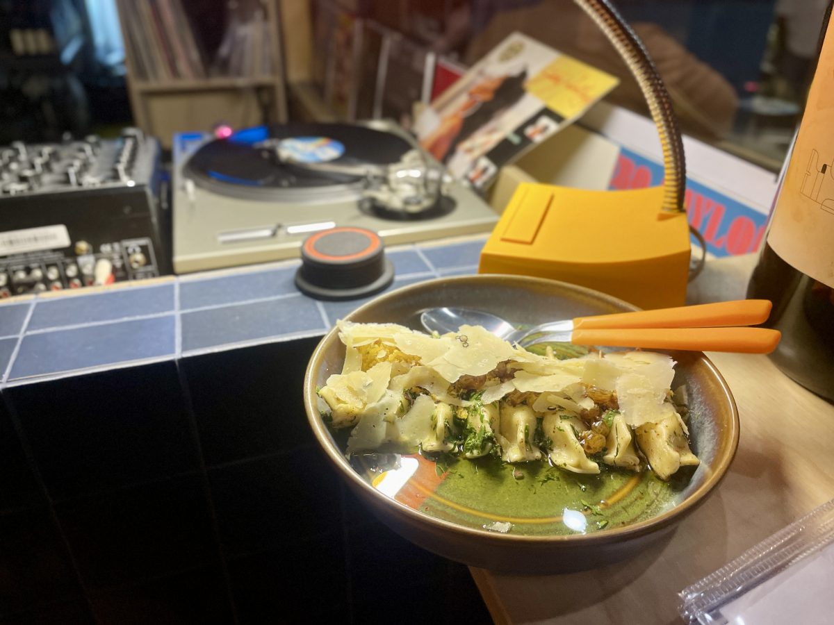 A plate of pasta on a bar with a record player in the background. 