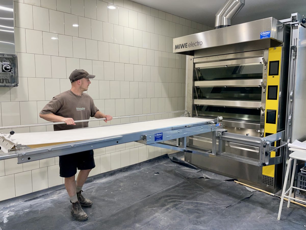 Man adjusts a rack on a large commercial oven. 