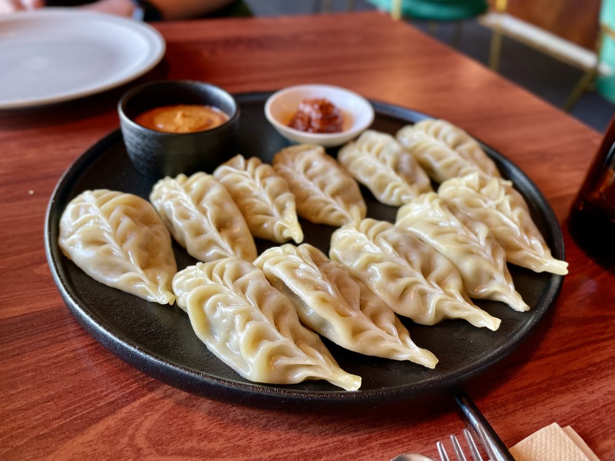 A black plate covered in steamed leaf shaped dumplings.