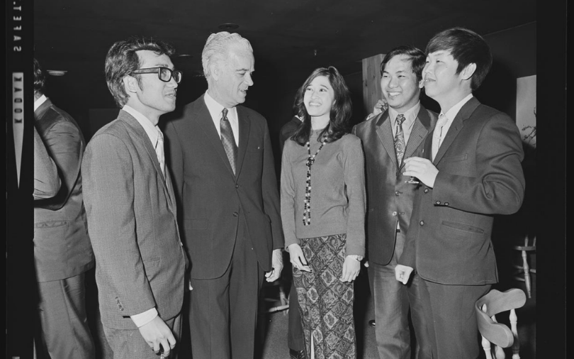 Four men and a woman in conversation while wearing business attire.