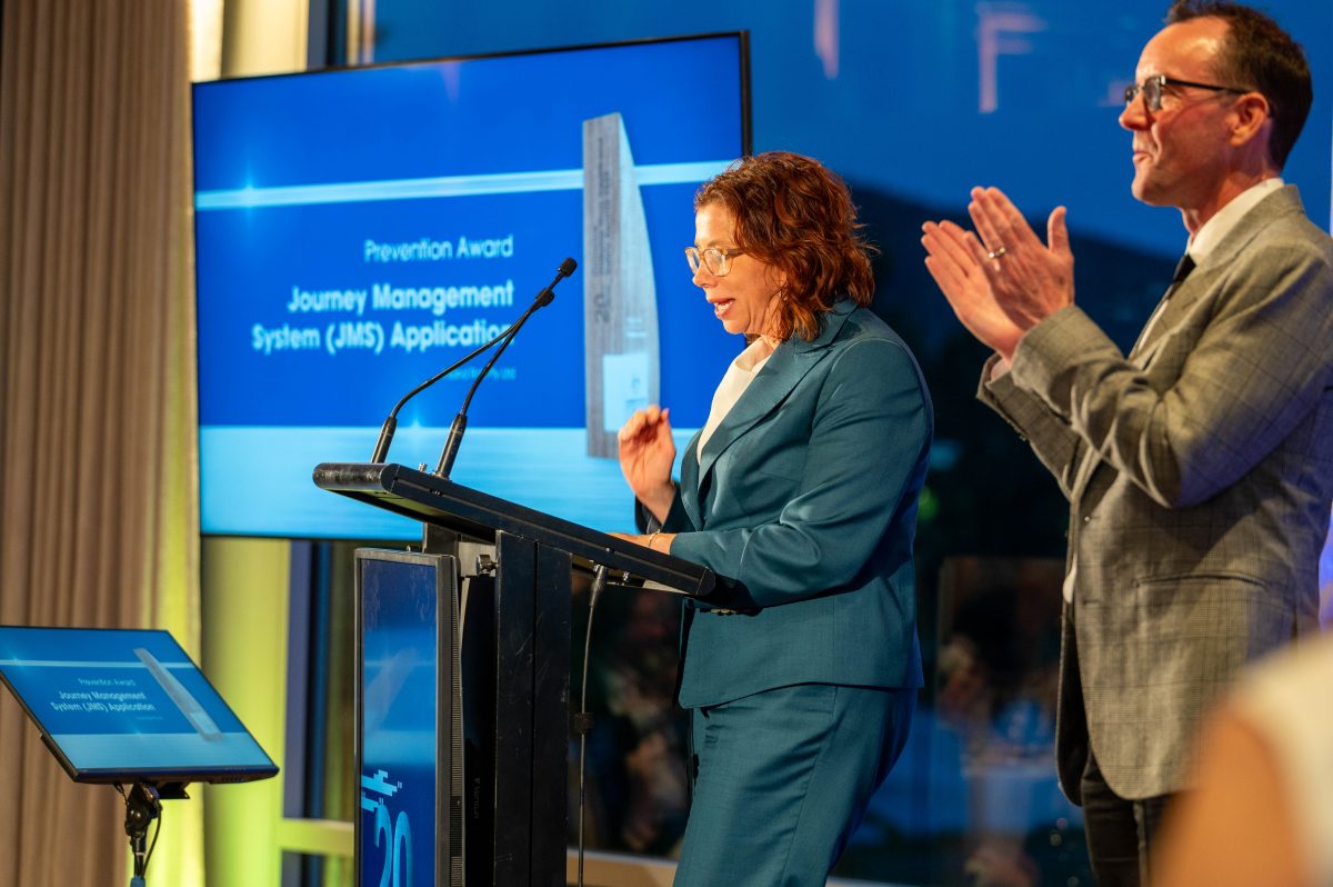 A woman speaking at a lectern while a man claps