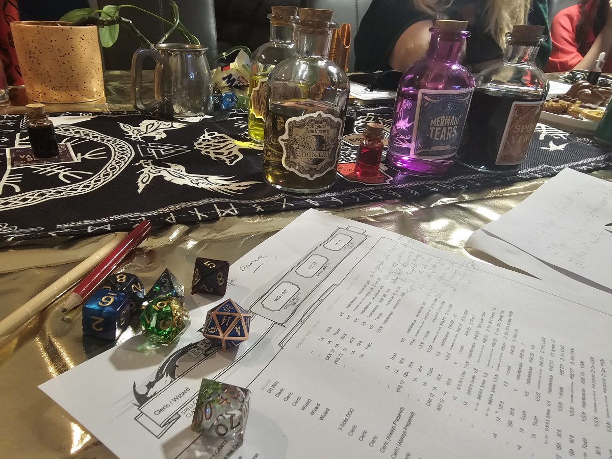 A table decorated with Dungeons & Dragons paraphernalia, including several colourful dice and flagons of colourful liquids.