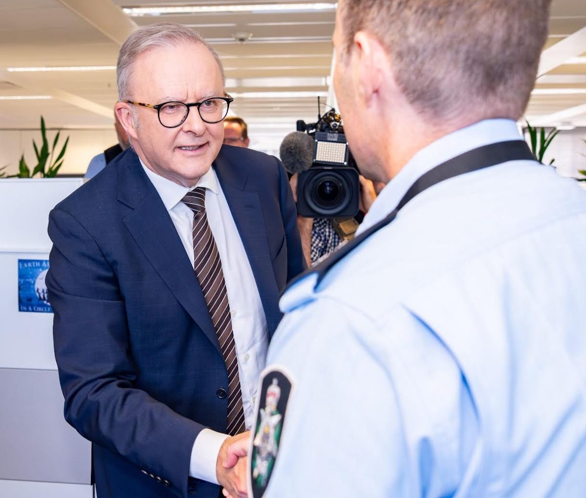 Man is suit shaking hands with a police officer who has his back to the camera