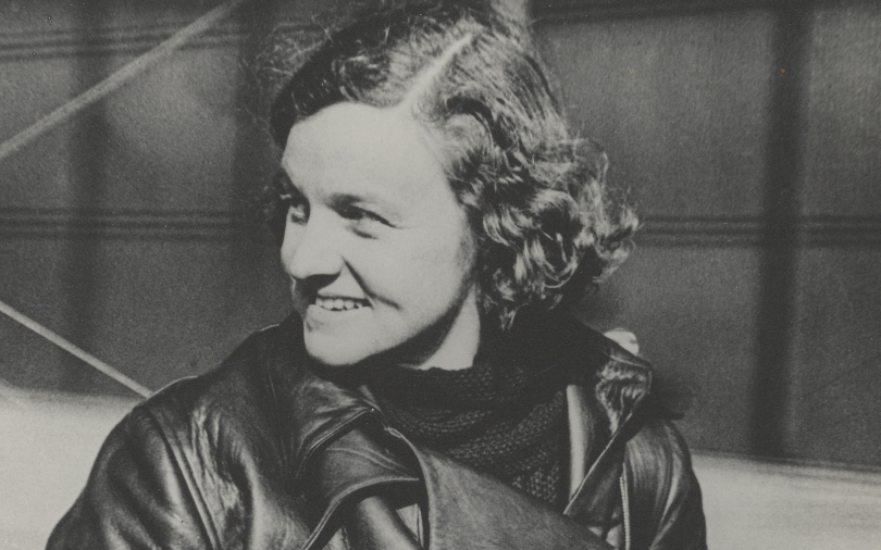 A sepia photograph of a woman with curly hair in flight gear