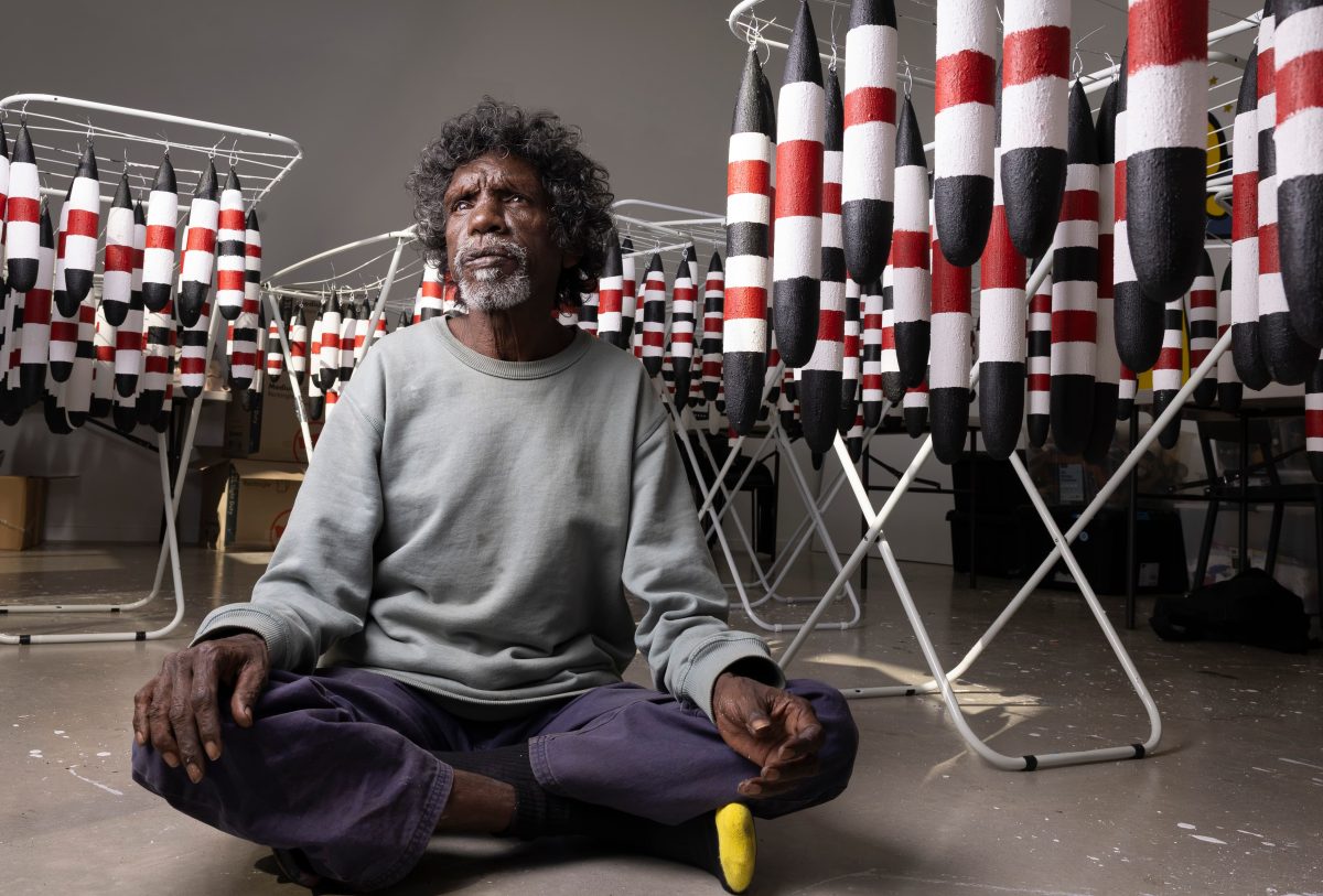 Aboriginal artist seated amongst his flying foxes sculptures