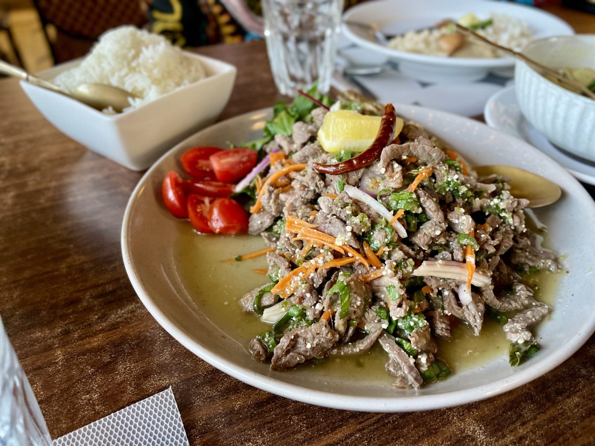 A plate with a heap of beef and vegetables. A whole dried chilli sits on top. 