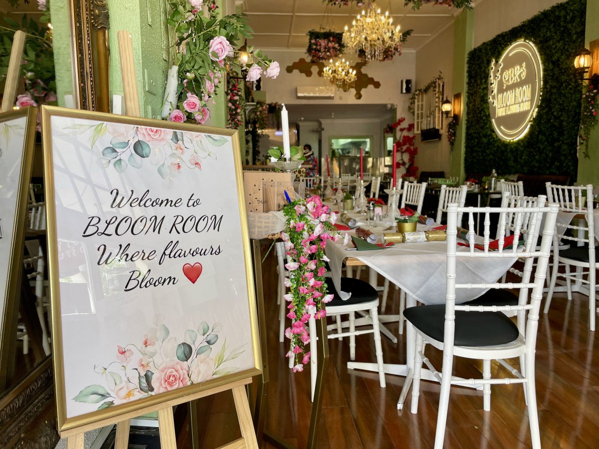Interior of restaurant with A-frame reading "Welcome to Bloom Room where flavours bloom"