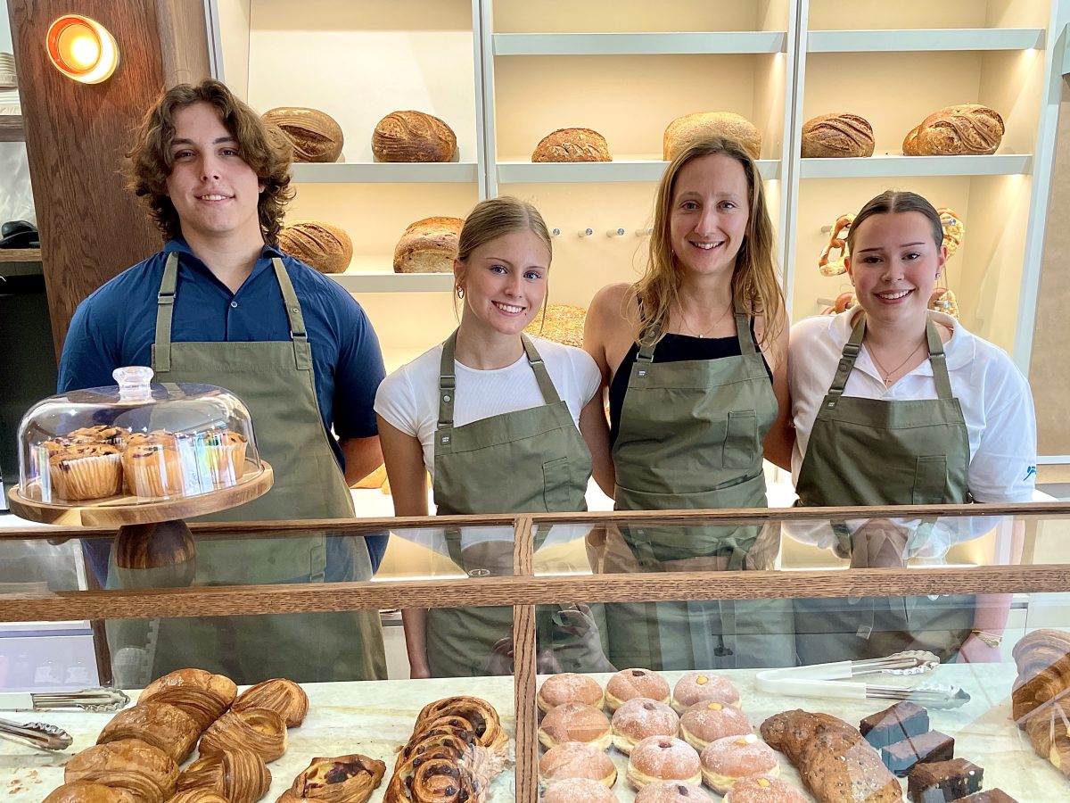 A group photo of one tall young man and three shorter young women.