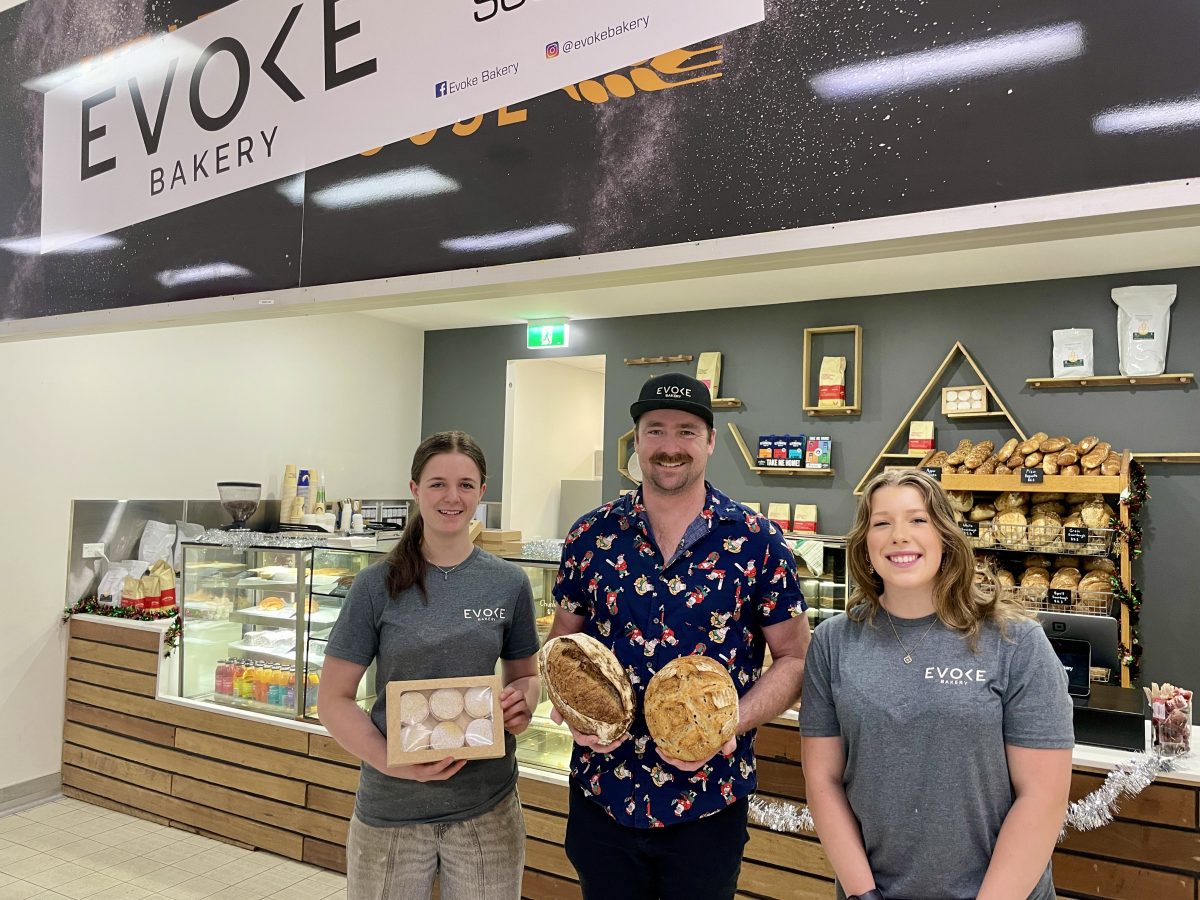Three people stand in front of a bakery counter