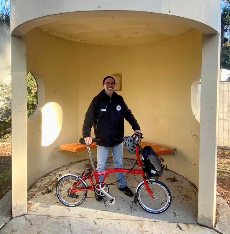 man standing with a bike inside a Canberra bus shelter