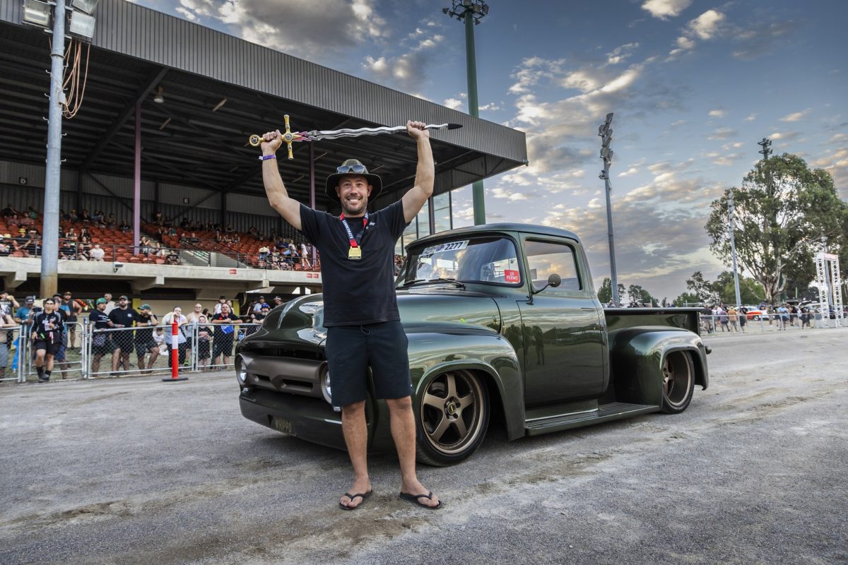 man holding a sword while standing with a car