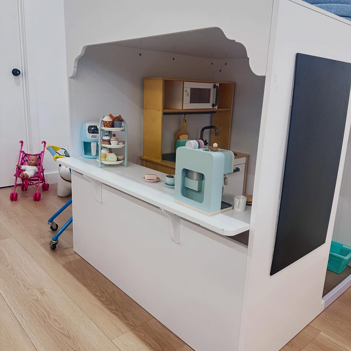 A child-sized cafe set up with toy coffee machine and wooden cupcakes.