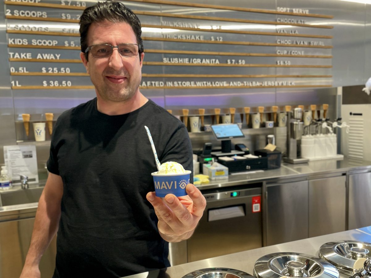 A man in a black shirt holds a cup of gelato which reads Mavi.