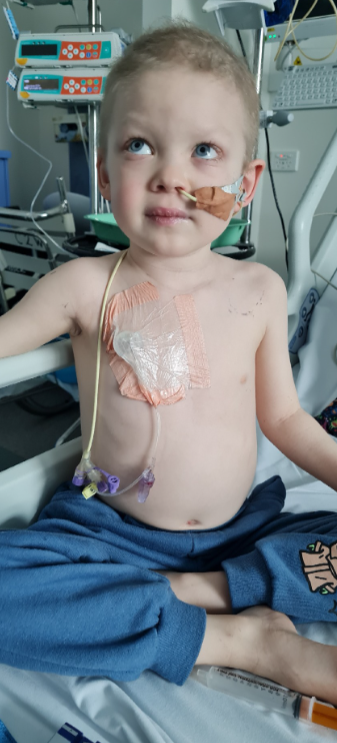 little boy in a hospital bed with tubes