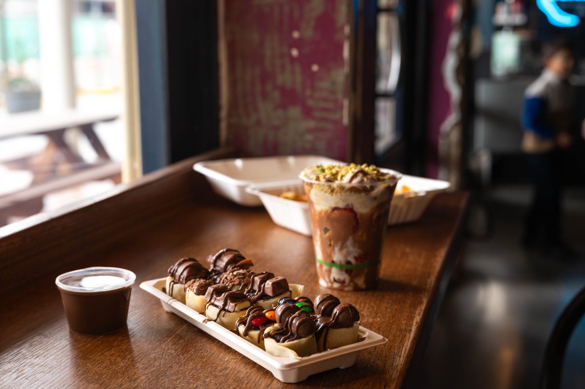 a chocolate-topped dessert sits on a bench with other food.