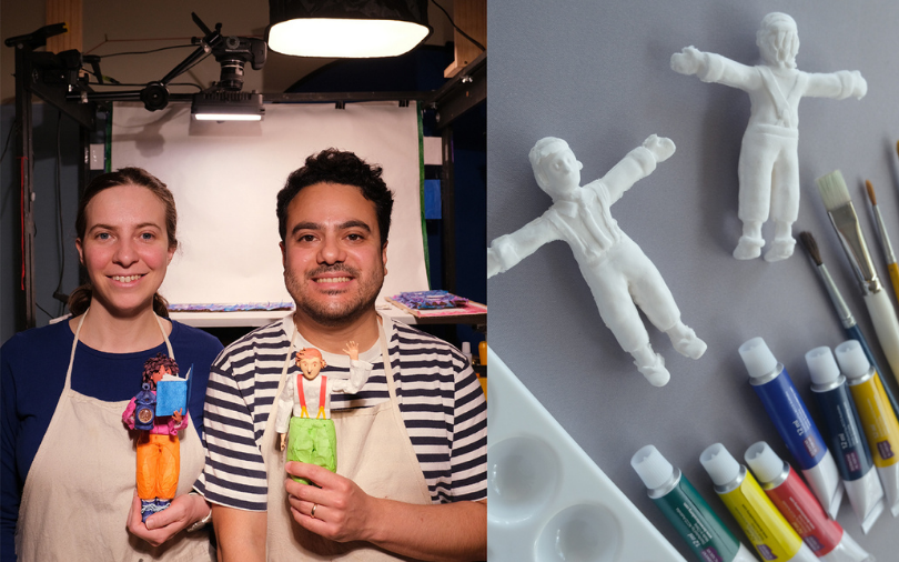 A woman and a man posing while holding painted figurines with craft supplies