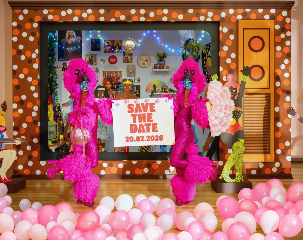 two costumed pink characters standing in front of Super Kaylene Whiskey exhibition holding a Save the Date sign