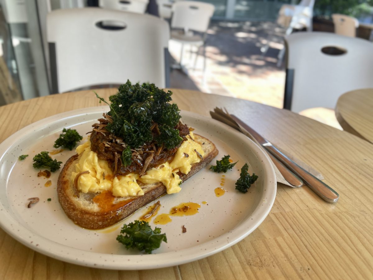 A plate with scrambled eggs topped with a sambal containing very small dried anchovies, and some crispy fried curly kale.